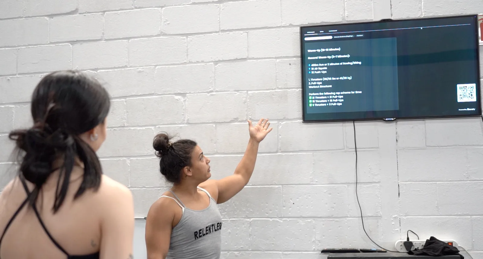 Coach pointing to the workout of the day on the gym screen
